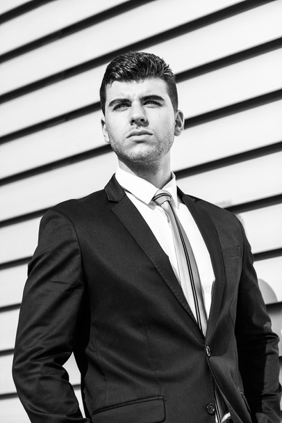Young businessman near a office building wearing black suit - Foto, afbeelding