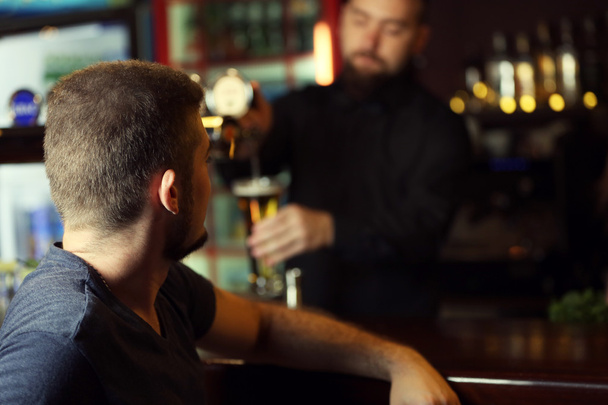 man drinking beer in bar - 写真・画像