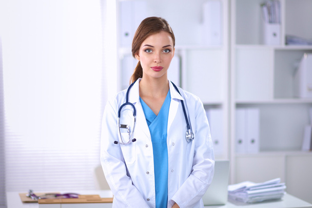 Retrato de una joven doctora con una bata blanca de pie en el hospital - Foto, Imagen
