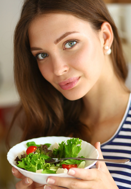 Nuori nainen syö salaattia ja pitää sekoitettu salaatti
  - Valokuva, kuva