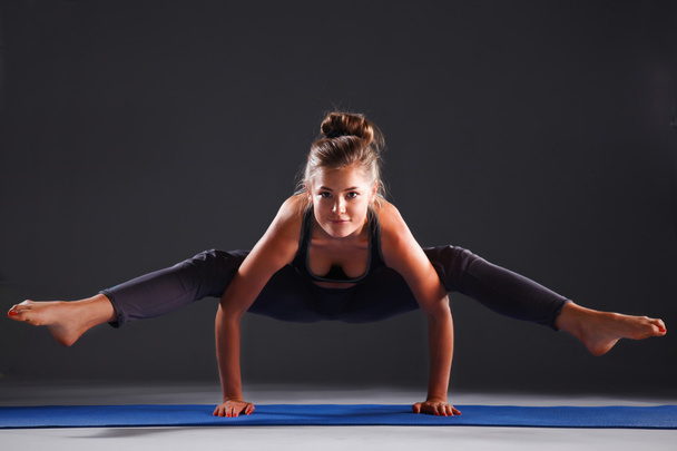 Young woman doing yoga exercise on mat - Fotó, kép