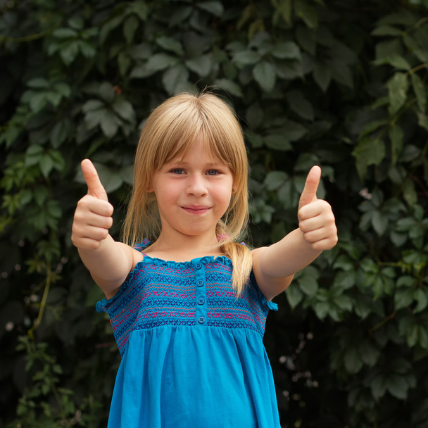 Laughing girl with daisy showing thumbs up - Photo, Image