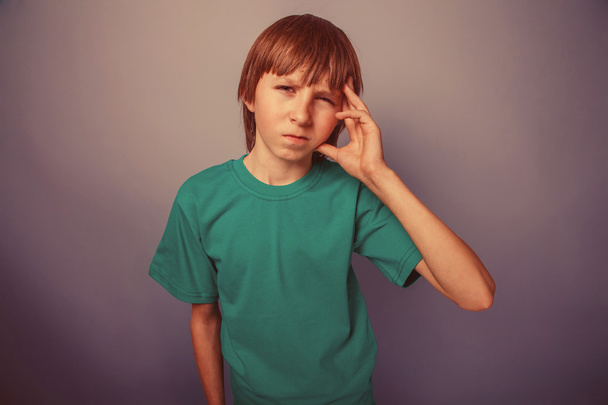 europäisch aussehender zehnjähriger Junge mit Kopfschmerzen, Migräne auf grauem B - Foto, Bild