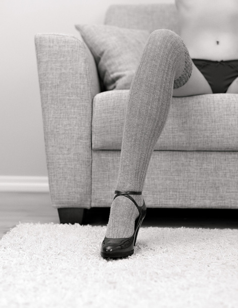 Femme avec de belles jambes assises sur le canapé. Noir et blanc
. - Photo, image