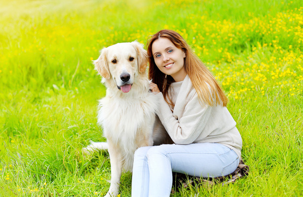 glückliche Besitzerin und Golden Retriever Hund sitzen zusammen auf dem Gras - Foto, Bild