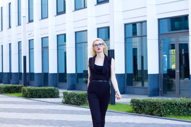 Intelligent woman walks down the street against the background of the business center - 写真・画像