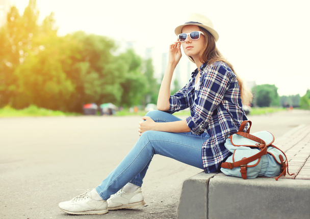 Pretty woman wearing a sunglasses, straw hat and backpack sittin - Zdjęcie, obraz