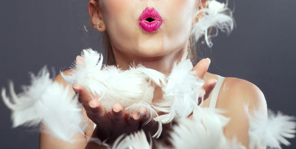 Girl blows in feathers. - Foto, afbeelding
