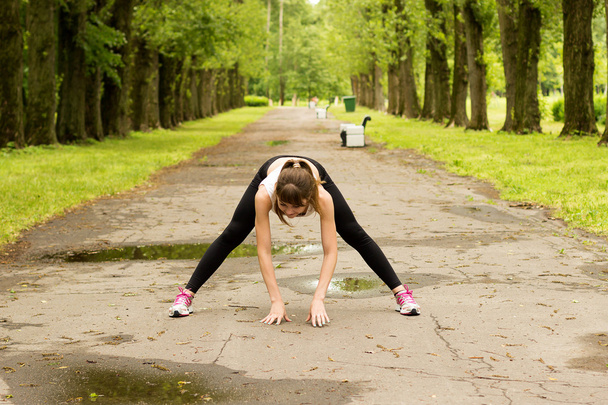 Young woman warming up in park before jogging - Foto, imagen