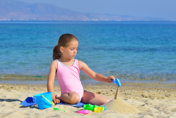 Чарівна дівчинка-малюк грає зі своїми іграшками на пляжі
 - Фото, зображення