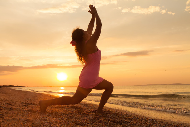 Νεαρό κορίτσι στην παραλία με την Ανατολή κάνει γιόγκα άσκηση - Φωτογραφία, εικόνα