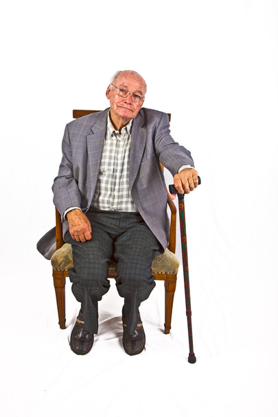 Velho homem amigável sentado em sua poltrona com bengala
 - Foto, Imagem