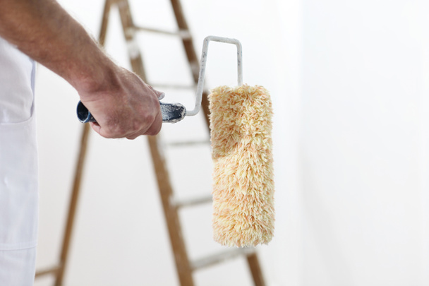 Pintor hombre en el trabajo con un rodillo de pintura y escalera, de cerca
 - Foto, imagen