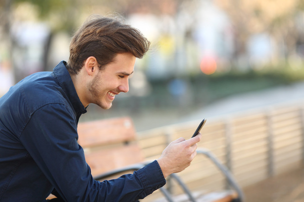 Szczęśliwy facet za pomocą smartfona w parku - Zdjęcie, obraz