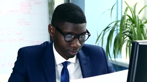 African American with glasses and a business suit carefully studying charts. - Séquence, vidéo