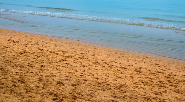 Παραλία Ακτή με τα ίχνη των ποδιών και μια ήρεμη θάλασσα - Φωτογραφία, εικόνα