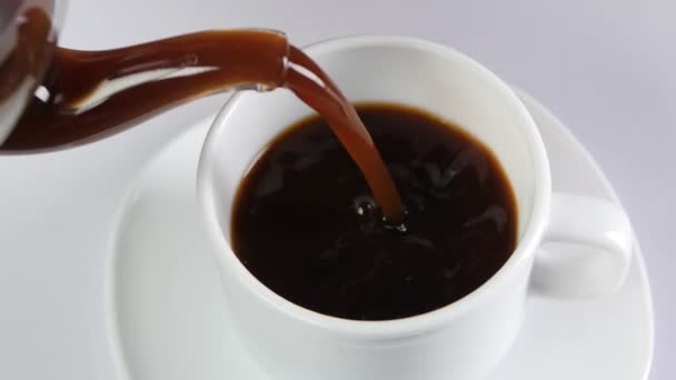 Pouring coffee into a cup on white background, slow motion - Felvétel, videó