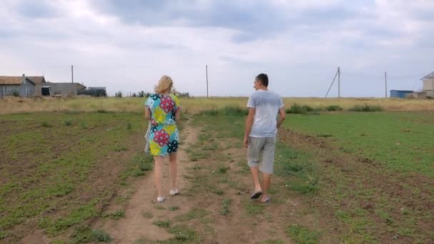 Mężczyzna i kobieta spacerujący wzdłuż drogi - Materiał filmowy, wideo