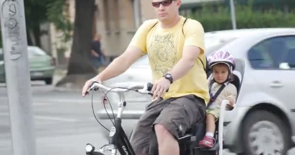 Uomo in giallo t-shirt e occhiali da sole cavalca sulla moto con il bambino si ferma vicino al marciapiede diverse auto passano da asfaltata Auto Road Close View
 - Filmati, video