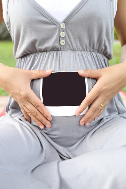 Pregnant women show ultrasound film picture on her belly. - Photo, Image