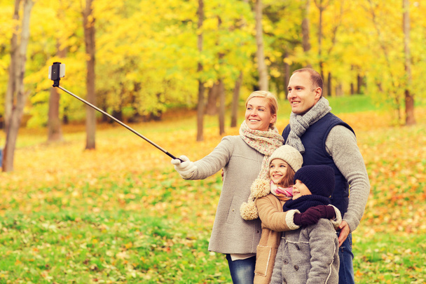 happy family with smartphone and monopod in park - Zdjęcie, obraz