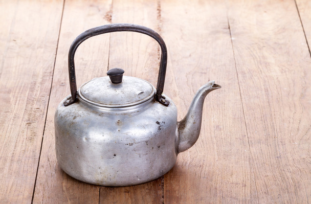 dirty classic aluminum kettle on wooden background - Foto, afbeelding