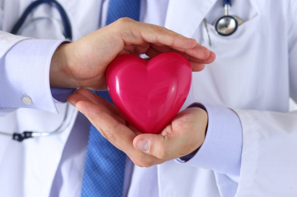 Medicina masculina médico mãos segurando e cobrindo vermelho brinquedo coração - Foto, Imagem