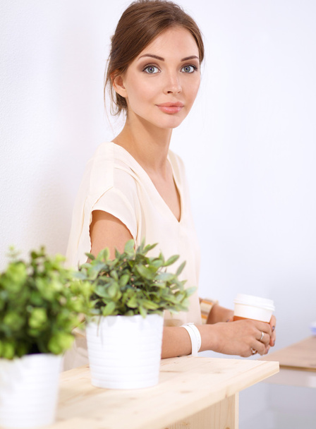 Beautiful woman holding pot with a plant, standing - Фото, зображення