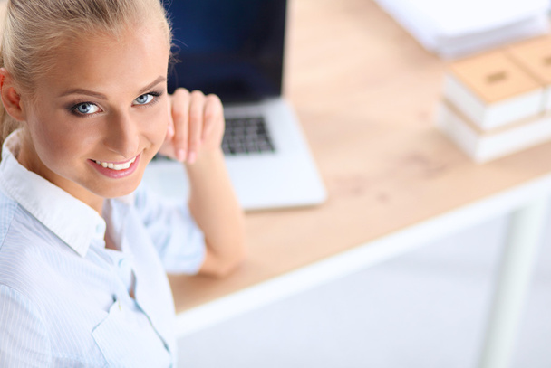 Attractive businesswoman sitting on a desk with laptop in the office - Foto, imagen