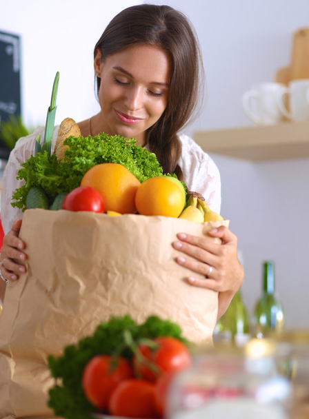 Young woman holding grocery shopping bag with vegetables and fruit - Фото, изображение