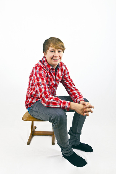 Friendly looking young boy with red shirt sitting on a wooden sc - Foto, afbeelding