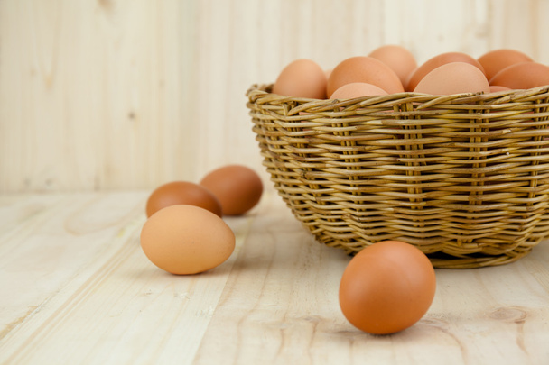 Full of Eggs put in a wicker basket in wooden background - Foto, afbeelding