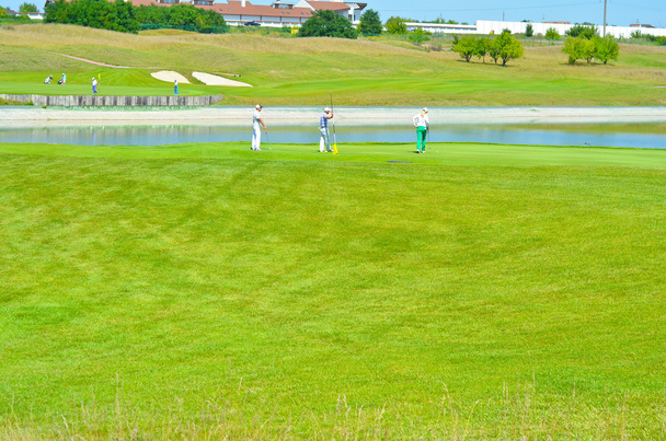 Люди играют в гольф на поле для гольфа
 - Фото, изображение