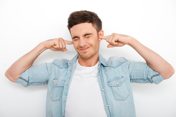 Frustrated young man holding fingers in ears - Photo, image