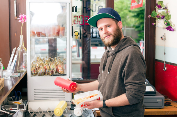 salesman making hotdog in fast food snack bar - Photo, Image