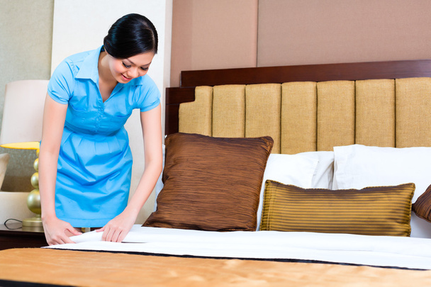 Chambermaid making bed in Asian hotel room - Foto, Imagem