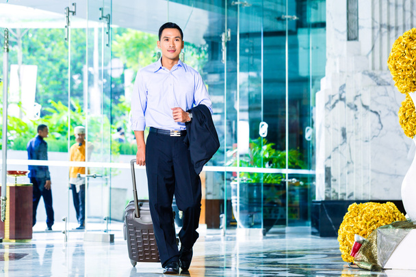 Asian man walking in hotel lobby - Photo, Image