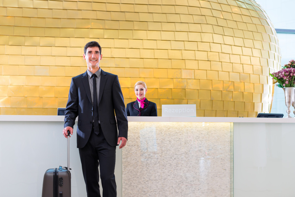 Man departing on business trip at hotel reception - Photo, Image