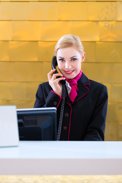 Hotel receptionist with phone on front desk - 写真・画像