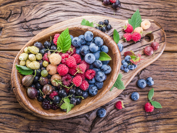 Ripe berries in the wooden bowl. - Фото, изображение