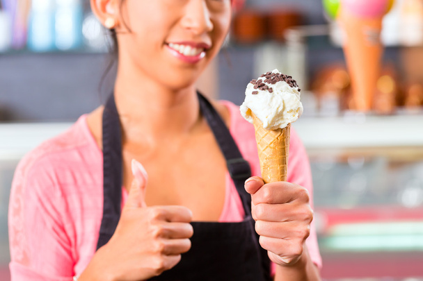 Жіночий продавець в салоні з конусом морозива
 - Фото, зображення