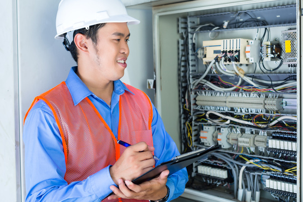 Electricista asiático en panel en obra
 - Foto, imagen