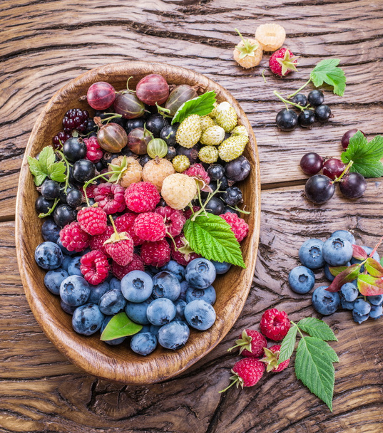 Ripe berries in the wooden bowl. - Zdjęcie, obraz