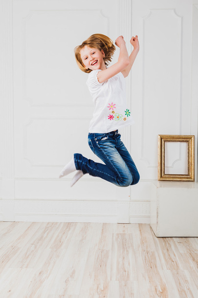 Happy girl jumping in light room - Foto, afbeelding