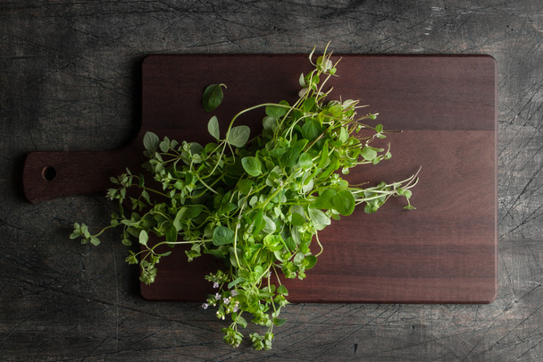 Oregano on the kitchen board on the old dark table - Foto, afbeelding