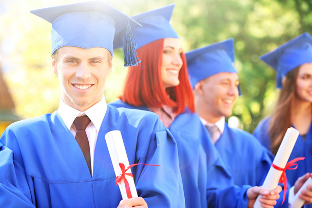 Estudiantes graduados en sombreros y batas de graduación, al aire libre
 - Foto, imagen