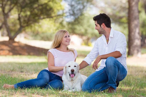 Young couple with old senior labrador dog in the park - Photo, Image