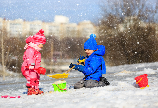 pieni poika ja tyttö kaivaa lunta talvella
 - Valokuva, kuva
