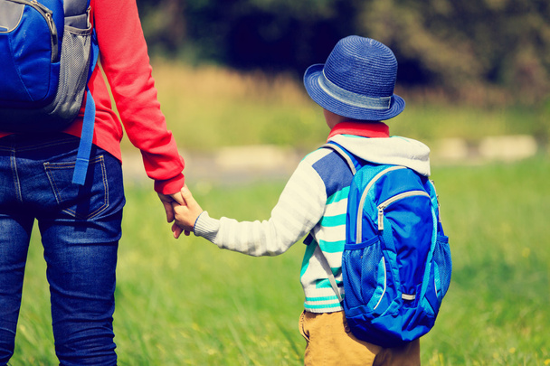 Mother holding hand of little son with backpack outdoors - Foto, imagen