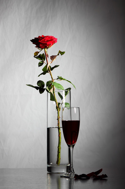 Vase with rose and glass of wine on the background of a brick wall - Photo, Image